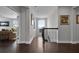 Bright hallway with hardwood floors, decorative art, and staircase with views into a sunny living area at 15208 Lake Claire Overlook Dr, Winter Garden, FL 34787