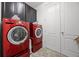 Well-equipped laundry room with modern, high-efficiency, red washer and dryer units and ample cabinet space at 15208 Lake Claire Overlook Dr, Winter Garden, FL 34787