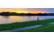 Scenic pond view reflecting a vibrant sunset sky, surrounded by lush green landscape at 15208 Lake Claire Overlook Dr, Winter Garden, FL 34787
