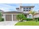 Beautiful home featuring a two-car garage, manicured lawn, and lush tropical landscaping at 15947 Vetta Dr, Bella Collina, FL 34756