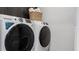 Laundry room featuring modern washer and dryer with sleek black trim and overhead storage at 1618 Bellagio Loop, Tavares, FL 32778