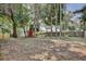 Large backyard featuring mature trees, a wooden fence, and a storage shed with a red door at 2320 Wekiva Ridge Rd, Apopka, FL 32712