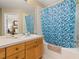 Bathroom featuring a shower-tub combo with a tiled curtain, single sink vanity, and a large mirror at 2346 Silver Palm Dr, Kissimmee, FL 34747