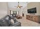 Bright living room features vaulted ceiling, ceiling fan, sectional sofa, and entertainment center at 2445 Ravendale Ct, Kissimmee, FL 34758