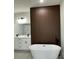 Modern bathroom featuring a soaking tub, wood accent wall, double sink vanity, and black fixtures at 3063 Sw 168Th Loop, Ocala, FL 34473
