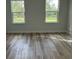 A bright bedroom featuring wood-look floors and two windows at 3063 Sw 168Th Loop, Ocala, FL 34473