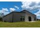 Spacious backyard with lush grass and a modern home design featuring large windows and a sliding glass door at 346 Bowfin Ct, Kissimmee, FL 34759