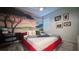 Modern bedroom featuring a red-framed bed, decorative wall art, and chic desk area at 3880 Sonoma Blvd, Kissimmee, FL 34741