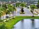View of a community entrance featuring palm trees, manicured lawns, and a small pond reflecting the landscape at 3880 Sonoma Blvd, Kissimmee, FL 34741