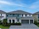 A modern two-story home boasts a three-car garage, well-maintained lawn, and stylish teal and gray color scheme at 3880 Sonoma Blvd, Kissimmee, FL 34741