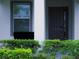 A modern front door and window are framed by lush green bushes and a sleek, light gray exterior at 3880 Sonoma Blvd, Kissimmee, FL 34741
