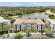 An eye-level aerial view of a large condo building featuring a red tile roof, multiple floors, parking, and lush landscaping at 4114 Breakview Dr # 30702, Orlando, FL 32819