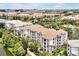 An eye-level aerial view of a large condo building with a parking lot, and lush landscaping by a pond at 4114 Breakview Dr # 30702, Orlando, FL 32819