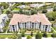 An eye-level aerial view of a large condo building featuring a red tile roof, multiple floors, and lush landscaping at 4114 Breakview Dr # 30702, Orlando, FL 32819