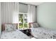 Bright bedroom featuring two twin beds with patterned bedding and a window view of the yard at 4536 N Landmark Dr, Orlando, FL 32817