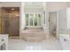 Bright main bathroom featuring a walk-in shower, soaking tub, and white tile flooring at 4536 N Landmark Dr, Orlando, FL 32817