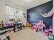 Playful bedroom with toys, a large window, and a stylish dark blue accent wall at 4553 Baler Trails Dr, St Cloud, FL 34772