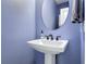 Stylish powder room featuring a pedestal sink, decorative mirror, and muted blue walls at 4630 Socrates Way, Sanford, FL 32773