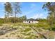 View of the back of a modern home, set on a spacious lot with a mix of natural sandy areas and greenery at 501 Marion Oaks Golf Way, Ocala, FL 34473