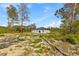 View of a single-story house, highlighting the expansive backyard with native vegetation and sandy soil at 501 Marion Oaks Golf Way, Ocala, FL 34473
