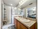 Bathroom with double sinks, granite countertop, glass shower, and view into main bedroom at 5420 Windsor Lake Cir, Sanford, FL 32773
