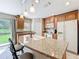 Well-lit kitchen with a granite countertop island, wooden cabinets, and a garden view at 5420 Windsor Lake Cir, Sanford, FL 32773