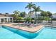 Community pool with lounge chairs, lush landscaping, and a black metal fence under a clear blue sky at 5420 Windsor Lake Cir, Sanford, FL 32773