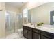 Modern bathroom featuring a glass-enclosed shower, double vanity with dark cabinets, and large mirror at 671 Drop Shot Dr, Davenport, FL 33896