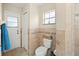 Bathroom featuring tiled walls, toilet, door to exterior, and a window at 6975 Maverick Trl, St Cloud, FL 34771