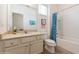 Well-lit bathroom featuring a shower-tub combo, tiled walls, wood look flooring, and a granite countertop vanity at 7017 Oakwood St, Davenport, FL 33837