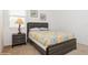 A cozy bedroom featuring a grey wood bed frame, decorative pillows, and a charming bedside table with lamp at 7017 Oakwood St, Davenport, FL 33837