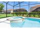 Beautiful swimming pool with attached hot tub, set within a screened-in lanai and lush landscaping at 7017 Oakwood St, Davenport, FL 33837
