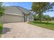 Attractive single-story home displaying a green lawn and neutral stucco exterior with a brick driveway and a green front door at 714 Home Grove Dr, Winter Garden, FL 34787