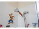 Close up of a shower head with Mickey Mouse & Friends decals on the shower walls at 8419 Pippen Dr, Orlando, FL 32836