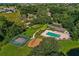 Aerial view showcases a community pool, tennis court, playground, and green spaces within a lush, wooded neighborhood at 920 Cool Springs Cir, Ocoee, FL 34761