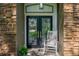 Inviting front porch with double doors, stone accents, and a cozy rocking chair at 920 Cool Springs Cir, Ocoee, FL 34761