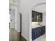 Stylish wet bar with navy cabinets, gold hardware, a countertop sink, and glass shelving for elegant storage at 960 Brightwater Cir, Maitland, FL 32751