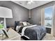 Comfortable bedroom with gray walls, a ceiling fan, and natural light from the large window with blinds at 10293 Cypress Knee Cir, Orlando, FL 32825