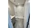 A well lit bathroom with marble-style tiling in the shower and gray wood-look flooring at 107 Grove St, Orlando, FL 32835