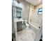 Bright bathroom featuring a vanity, toilet, and shower-tub combo with marble-patterned tiles and a window at 107 Grove St, Orlando, FL 32835