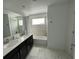 Modern bathroom with double sinks, dark cabinets, a tub, and marble-like tile at 1078 Splash Shot Pl, Davenport, FL 33896