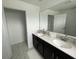Bright bathroom featuring double vanity with dark cabinets and a large mirror at 1078 Splash Shot Pl, Davenport, FL 33896