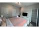 Cozy bedroom features a pastel pink quilt, white dresser with TV, and an open closet at 1078 Splash Shot Pl, Davenport, FL 33896