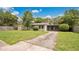 View of home with a well-maintained lawn, trees, and driveway leading to a screened in front porch at 1202 Randolph St, Sanford, FL 32771