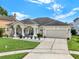 Well-maintained single-story home featuring a two-car garage, lush lawn, and decorative flower beds along the entrance at 14036 Cherry Bush Ct, Orlando, FL 32828