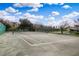 Community tennis court surrounded by lush greenery and a serene pond on a sunny day at 14036 Cherry Bush Ct, Orlando, FL 32828