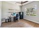 Bright office space with wood floors, ceiling fan, open shelving, and a large window with backyard views at 14205 Conifer Dr, Orlando, FL 32832