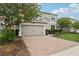 Charming two-story home with a brick driveway, manicured lawn and beautiful flowering tree at 1450 Chelsea Manor Cir, Deland, FL 32724