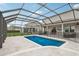 A beautiful screened-in pool area with a sparkling blue pool and travertine tile deck at 1450 Chelsea Manor Cir, Deland, FL 32724