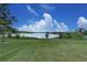 A beautiful, green backyard view with an iron fence overlooking a lake under a partly cloudy, blue sky at 16768 Sanctuary Dr, Winter Garden, FL 34787